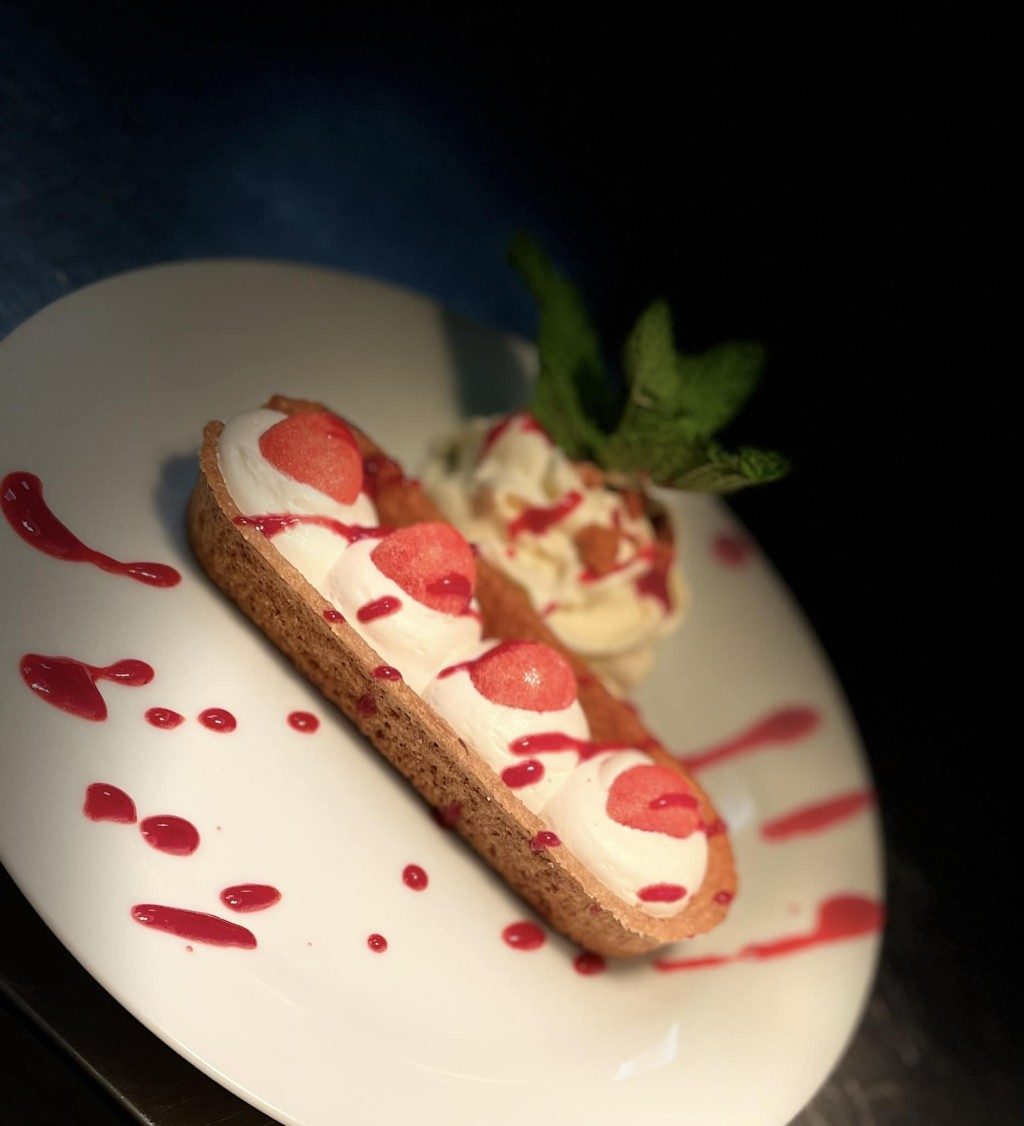 Un dessert au coulis de fruits rouges sur une assiette blanche
